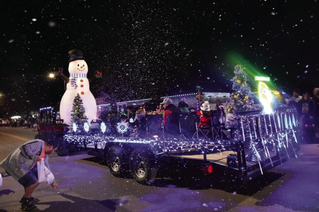LET IT SNOW—This cleverly rigged float from Crushing It won the Most Original award in the Lighted Christmas Parade December 8 in downtown Hereford. Making S’mores around a campfire while the float generated its own “snow” fall as it made its way down Main Street added to the appeal of the entry. (Photo by Jim Steiert)