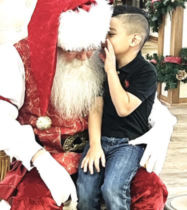 Hart Elementary student Messiah Minjarez whispers to Santa what he wasn’t for Christmas at the Happy State Bank of Hart annual Christmas event. Each year Hart students make a visit to Santa at the local bank.