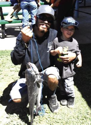 PEE WEE ANGLER-- Three-year-old Ismael Torres caught the biggest fish, a 27-1/2-inch channel catfish that was also good for first place in the Texas Junior angler event Saturday, May 16 at Josserand Aquatic Park Pond. Ismael was a little sleepy to pose with it, but selected the new bike offered among the selection of prizes for winning anglers. (Photo by Jim Steiert)
