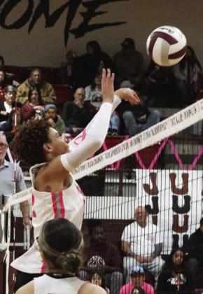 Naliyah Williams serves the ball Michelle Mott jumps up high over the net for the hit