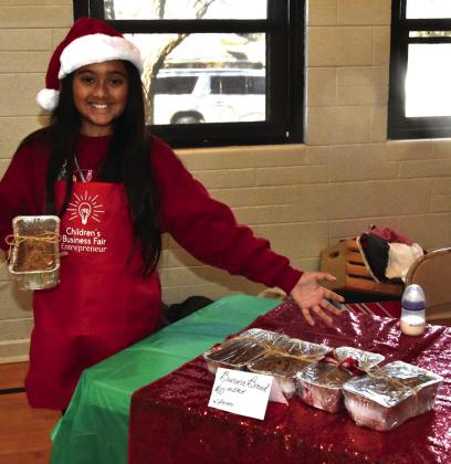 SWEETS BY LIZETTE—Lizette Lopez, 11, styles a loaf of her banana nut bread, one of the offerings at her Lizette’s Sweets booth.