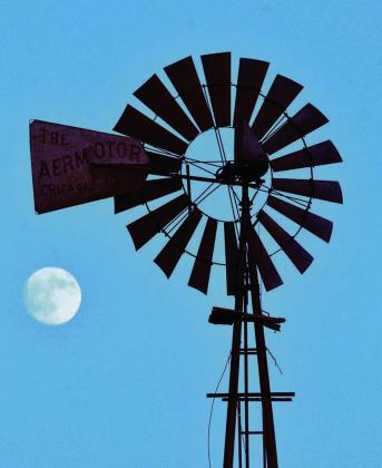 MOONING THE WINDMILL-- Maybe Mother Nature was having a little fun situating the almost-full October harvest moon like it was looking to hitch a ride on the tail of the spinning fan of a classic Aermotor windmill near Dawn Sunday evening, October 5, or maybe the moon was just showing off its natural features to the clanking tower-- bringer of underground rain to the Plains. (Photo by Jim Steiert)
