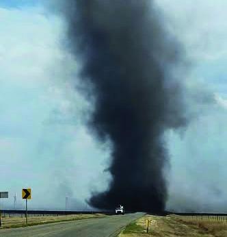 HELLISH FURY--A threatening black smokenado swirls behind an emergency vehicle on FM 168 south of Buffalo Lake at the height of May 14 and 15 wildfire raging in Randall County. Multiple fire departments including Hereford, Dawn, Bootleg, Hart and Nazareth responded.