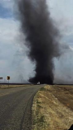 HELLISH FURY--A threatening black smokenado swirls behind an emergency vehicle on FM 168 south of Buffalo Lake at the height of May 14 and 15 wildfire raging in Randall County. Multiple fire departments including Dimmitt, Hereford, Dawn, Bootleg, Hart and Nazareth responded.