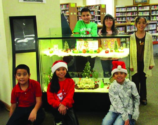 Display for the month of December, 2025, at Rhoads Memorial Library focuses on the Grinch. Family members of the library staff who are showing off the display are, kneeling from left, Francisco Medina, Ava Oltivero, and Andre Oltivero. Standing, from left, are Hugo Sanchez, Kehlani Oltivero, and Grace Medina.