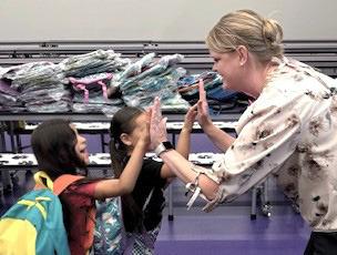 CCHD CEO Elisha Rosier gets a high five from students after they receive backpacks.