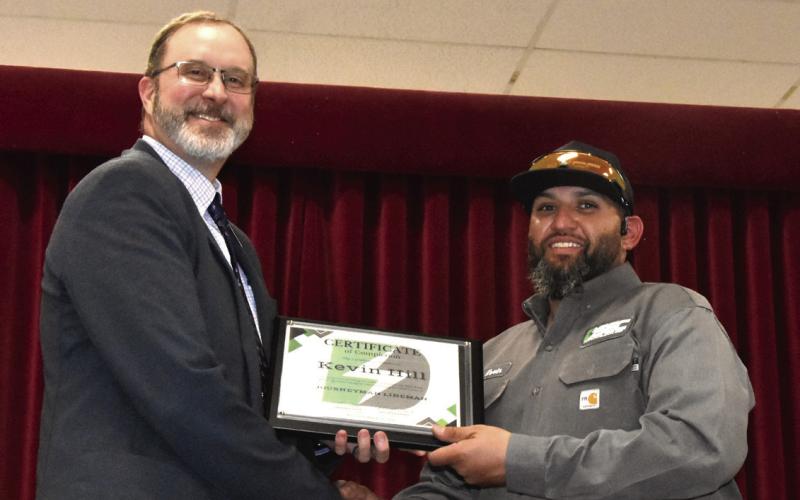 JOURNEYMAN LINEMAN--Deaf Smith Electric Cooperative President and General Manager Tim Burkhalter congratulates Kevin Hill on achieving Journeyman Lineman status with the Cooperative during the 88th annual Membership Meeting March 24 at the Hereford Bull Barn. (Photo by Jim Steiert)