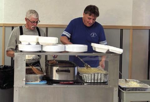 SERVING CHOW—Larry Carlson and Jim Layman serve up food at the Samaritan Hospice Dessert Auction and Brisket Dinner held November 25 at the Kings Manor Lamar Room.