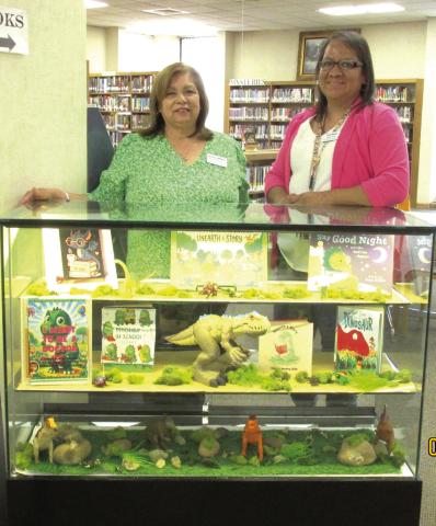 The theme of 'Unearth a Story' is featured as the Display for the months of June and July, 2026, at Rhoads Memorial Library. Sulema Oltivero, left, and Rosa Medina, library personnel, created the display to remind youngsters of the summer reading program that uses that theme.