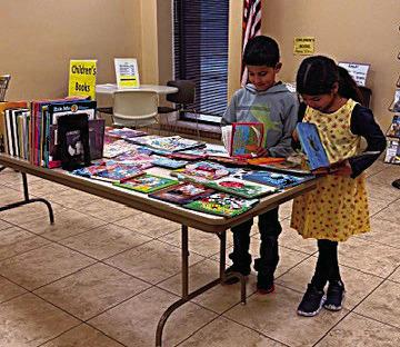 Siblings Andre and Ava Oltivero look at some of the children's books featured at this week's annual book sale at Rhoads Memorial Library. Fiction and non-fiction books are offered, too, along with movies, audio books, music CDs, and more.