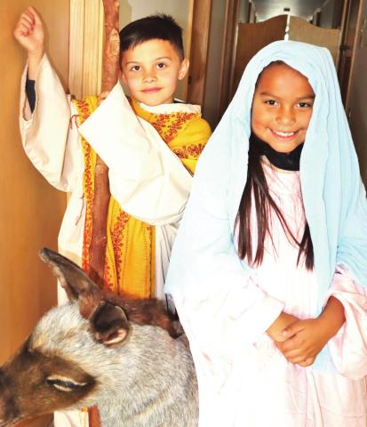 Traveling of Census — Crew Clark, left, and Jaselyn Gonzalez take on the attire of Joseph and Mary and pose with a prop donkey as they anticipate the upcoming “Walk Through Bethlehem” and a celebration of Las Posadas on Sunday, Dec. 5 at Saint Anthony School in Hereford.