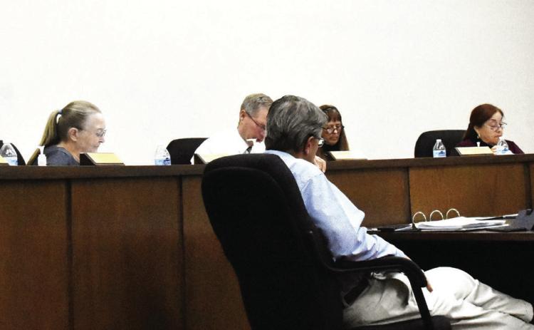 IT'S IN THE DETAILS--City commissioners examine a preliminary version of the proposed new city budget during a regular commission meeting July 6. In the foreground, City Attorney Audie Sciumbato and City Secretary Franchesca Jimenez pore over the details as well. (Photo by Jim Steiert)